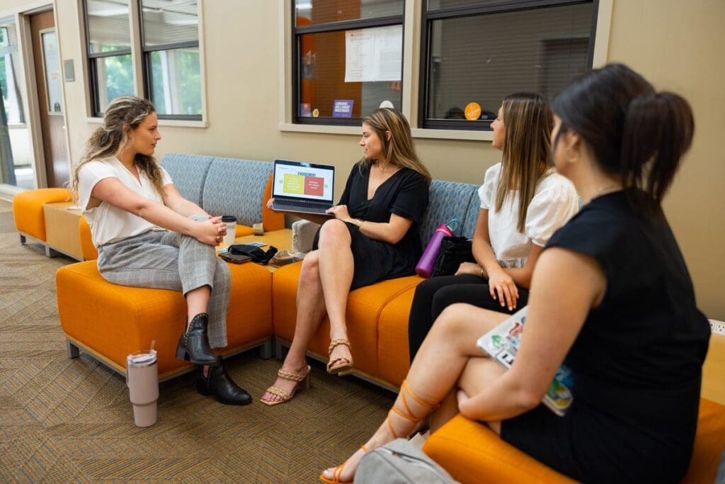 A group of students sit in the Communication and Information fourth-floor lobby.