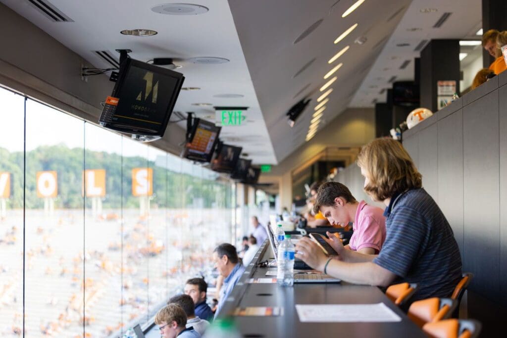 Journalism students sit in the box at Neyland Stadium while covering a football game.
