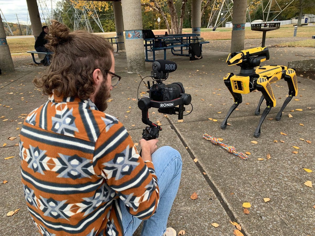 A student videos a robot dog for a story.