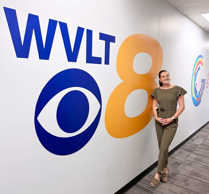 Student Nicole Marker stands next to a wall with the WVLT channel 8 logo.